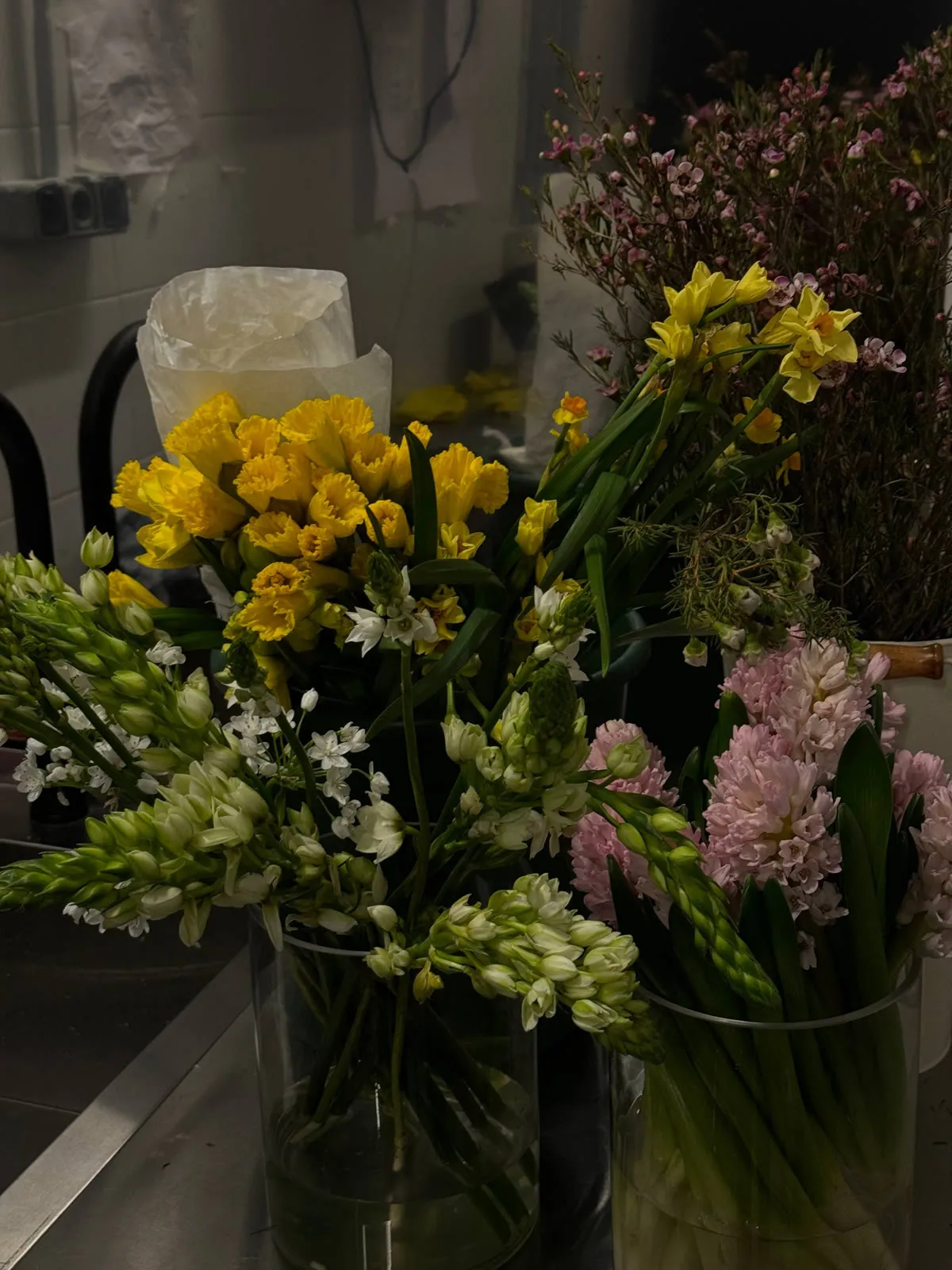 Daffodils, hyacinths, star-of-Bethlehem and waxflower in vases in the florist's workroom