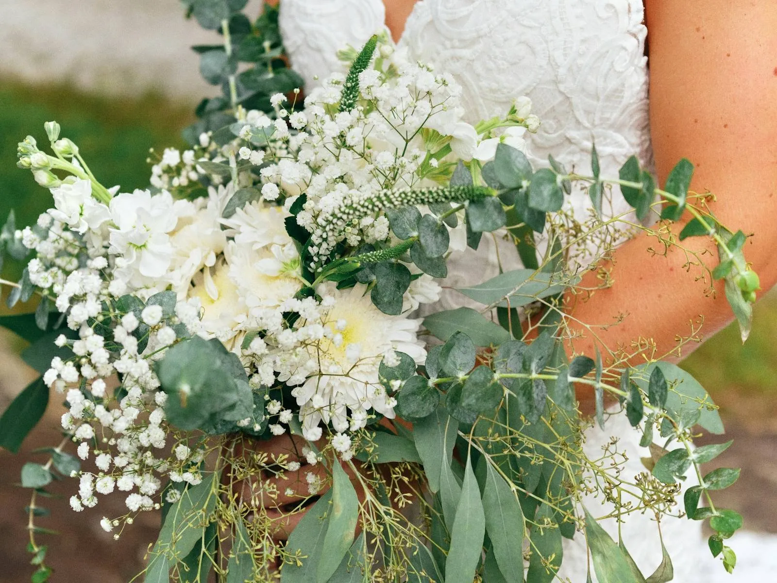 Ramo de novia de flores blancas, gipsófila y eucalipto sostenido por una novia con vestido de encaje