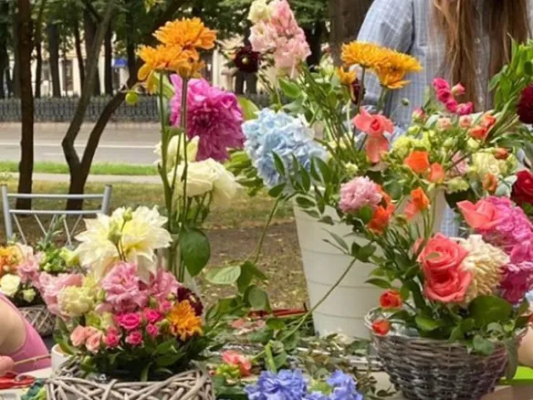 An outdoor floral workshop table with baskets of flowers and shears